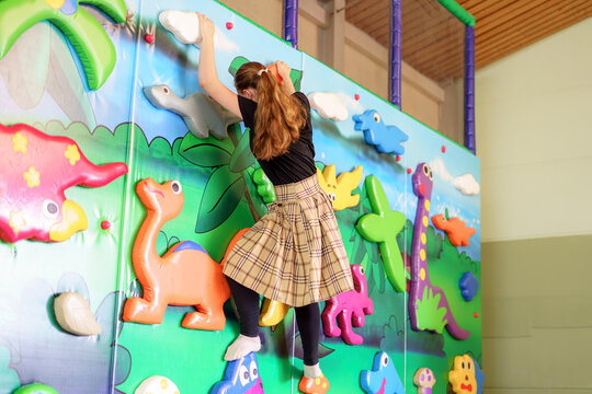 A girl overcomes obstacles on a children's extreme wall.