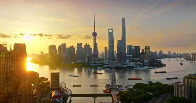 Aerial view of the iconic Shanghai Lujiazui skyline including famous skyscrapers by the Huangpu River during a stunning golden sunrise.