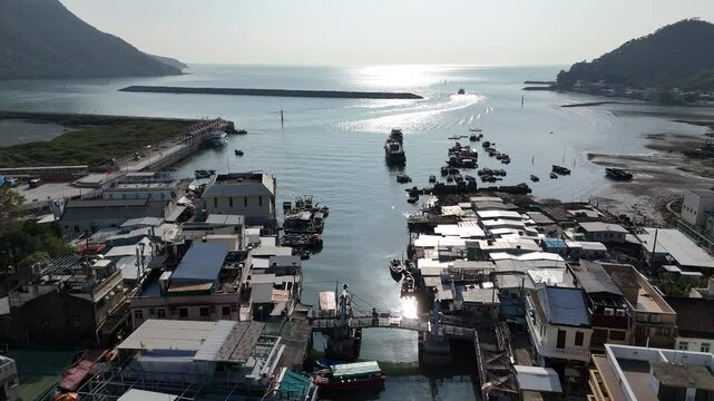 Aerial footage of Tai O harbour in the late afternoon light with the passenger ferry leaving the harbour.