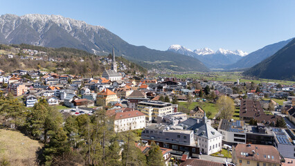 Obraz premium Aerial winter view of the city centre of Imst in Tirol. Beautiful city view with Rauchberg and Heiterwand mountain in the background and Pfarrkirche Imst. Tourist travel destination in Tyrol, Austria.