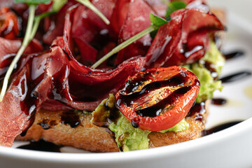 Gourmet prosciutto toast with avocado and balsamic sauce