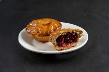 Juicy fresh ruddy pastries on a white plate on a dark gray background