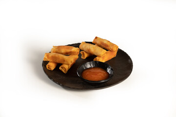 Tasty spring rolls with teriyaki sauce served in a black plate on white background, stock
