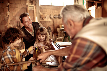 Happy multigenerational family building wooden project together in home workshop