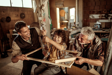 Three male generations working together on a woodworking project in family workshop