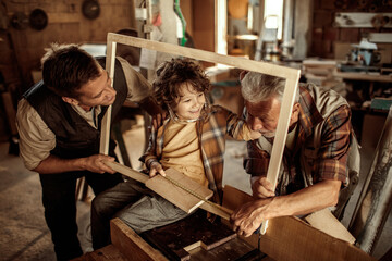 Three male generations working together on a woodworking project in family workshop