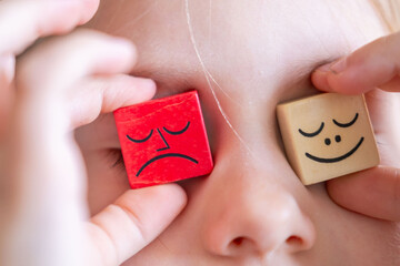 Wooden blocks with emotions, Child's hand playing with wooden blocks, emotional intelligence in early childhood, Diversity and inclusion