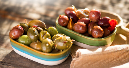 Olives, homemade marinated colorful olives with herbs and spices on rustic table, close up. Healthy Mediterranean vegan food, macro shot. 