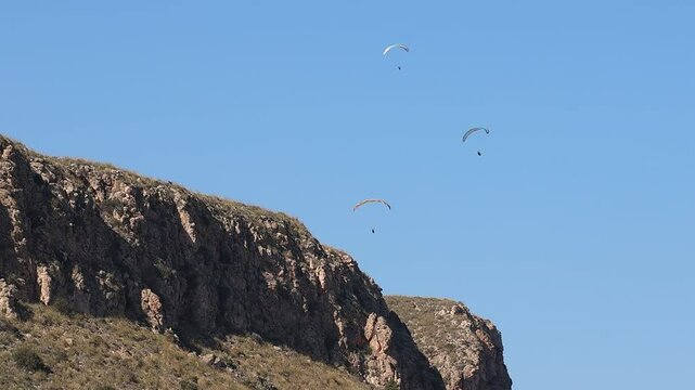 Grupo de parapentes volando con fondo de cielo azul sobre la monta&ntilde;a, Alicante, Spain