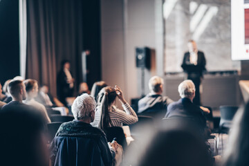 Speaker giving a talk in conference hall at business event. Rear view of unrecognizable people in...