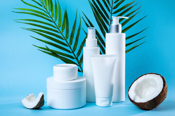 A stylish composition featuring white skincare bottles and jars, complemented by greenery and...