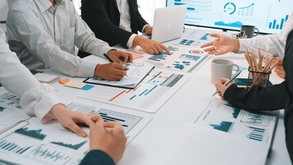 A diverse group of professionals collaborates in a bright office, engaged in meaningful discussions while analyzing charts and data to derive insights for business strategy. SACTR