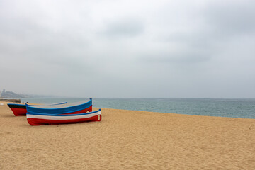 Fototapeta premium Two boats are sitting on the beach, one of which is blue and the other is red