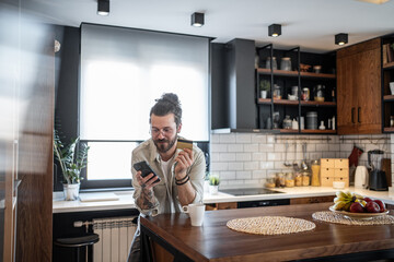 Freelancer making online payment using credit card and smartphone in modern kitchen
