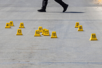 Law enforcement officer walking through a crime scene surrounded by evidence markers.
