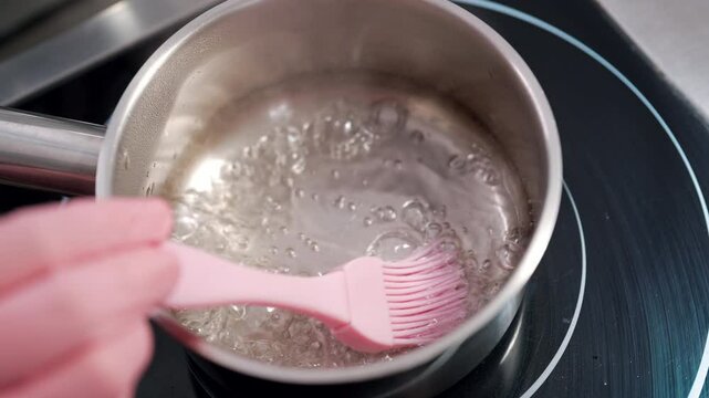 Preparing sugar syrup for soaking cake crust. Professional confectioner cooking