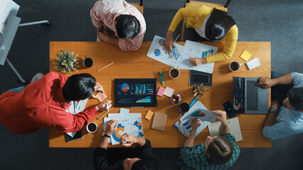 Top down view of investor brainstorming while looking at financial statistic document. Group of...