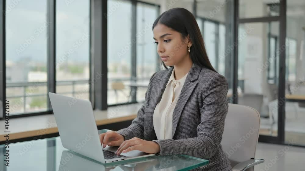 Aufkleber a woman sits at a table using a laptop computer.