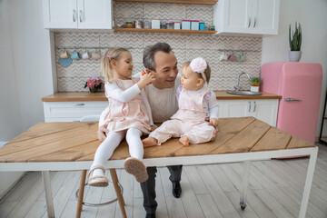 Daddy's girls. Cheerful father communicates with his two daughters in a modern and cozy kitchen. Father's day. Parenting. Loving home environment. International day of families. Children's Day