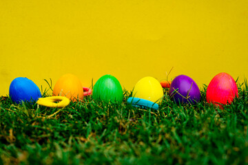 Easter Eggs in Green Grass against Vibrant Yellow Backdrop
