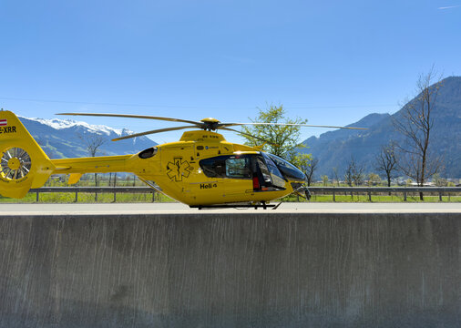 Yellow Austrian rescue helicopter stops on the highway to help the injured after an accident. Airbus H135