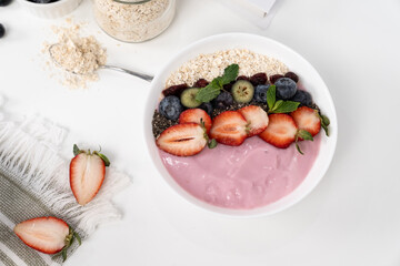 Presented by fruits putting yogurt toppings with strawberry, berry, oats, raisins and chia seed decorated by peppermint in white blow. Pink background. Set of healthy dairy product choice. Pecuniary.