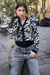 Fototapeta premium Fashion model posing in urban setting, wearing stylish cardigan and jeans