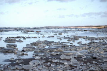 
icy beach with many pieces of ice on the sand and water.