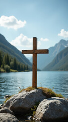Cross on rocky shore overlooking mountain lake.