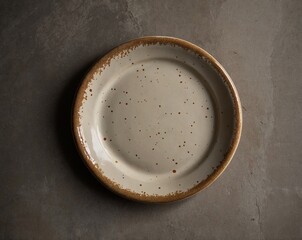 Handcrafted ceramic plate with matte cream base and brown speckles, irregular rim, placed on textured concrete surface with linen napkin and brass fork