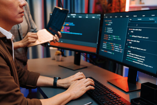 Serious of IT developers discussing intelligent website development coder system running data online two screens with laptop showing information network at neon light room at modern office. Infobahn.