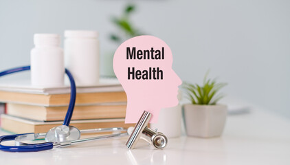 A head with the word Mental Health written on it is on a table with a stethoscope