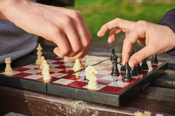 Two players engaged in a chess match outdoors, making strategic moves.
