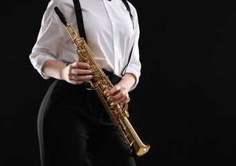 Fototapeta premium Musician with soprano saxophone on dark background, closeup. Space for text