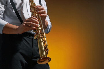 Naklejka premium Professional musician playing soprano saxophone on color background, closeup. Space for text