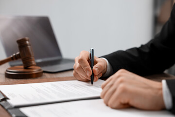 Notary signing document at table in office, closeup