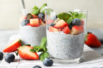 Delicious chia pudding with strawberries, blueberries and mint in glasses on table, closeup