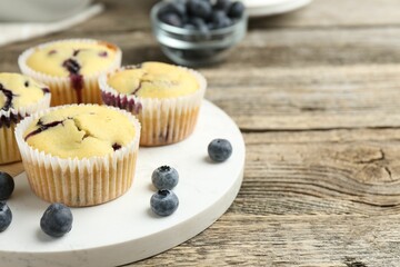 Delicious muffins with blueberries on wooden table, closeup. Space for text