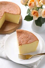 Tasty Japanese Castella sponge cake, flowers and fork on white table, closeup