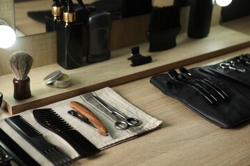 Many different barber's tools on light wooden table in barbershop