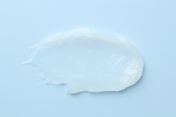 Moisturizing lip balm on light blue background, top view