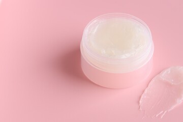 Moisturizing lip balm and jar on pink background, closeup. Space for text