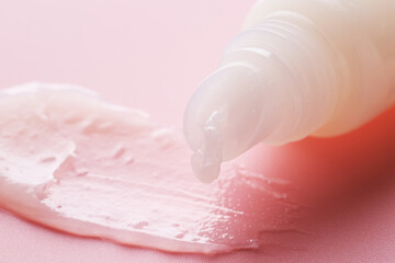 Tube with moisturizing lip balm on pink background, closeup