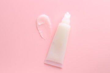 Tube with moisturizing lip balm on pink background, top view