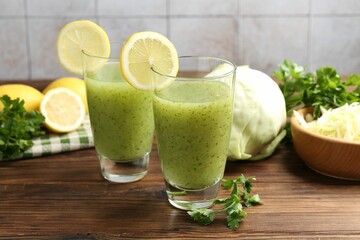 Healthy parsley drink in glasses, lemons and cabbage on wooden table, closeup