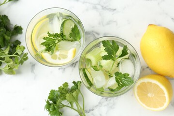 Healthy drink with parsley, cucumbers, lemon and celery on white marble table