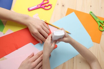 Mother and daughter making handmade project at wooden table, top view
