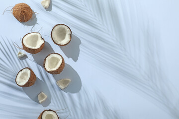 Fresh coconuts and shadow cast by tropical palm on light grey background, flat lay. Space for text