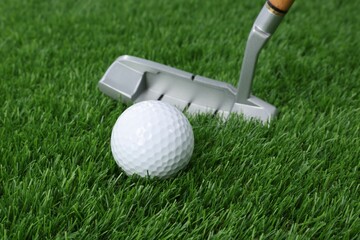 Golf ball and club on green grass, closeup