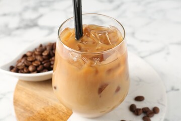Tasty iced coffee and beans on white marble table, closeup
